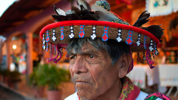 Hombre adulto mayor con sombrero huichol tradicional con plumas y chaquira